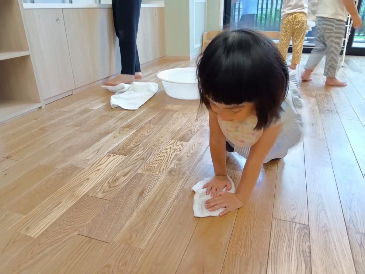 一人の子どもが膝をついて床を雑巾がけしている