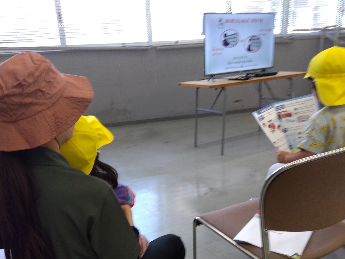 郵便局内では、大人の膝の上で映像を見る子、パンフレットを見る子などがいる