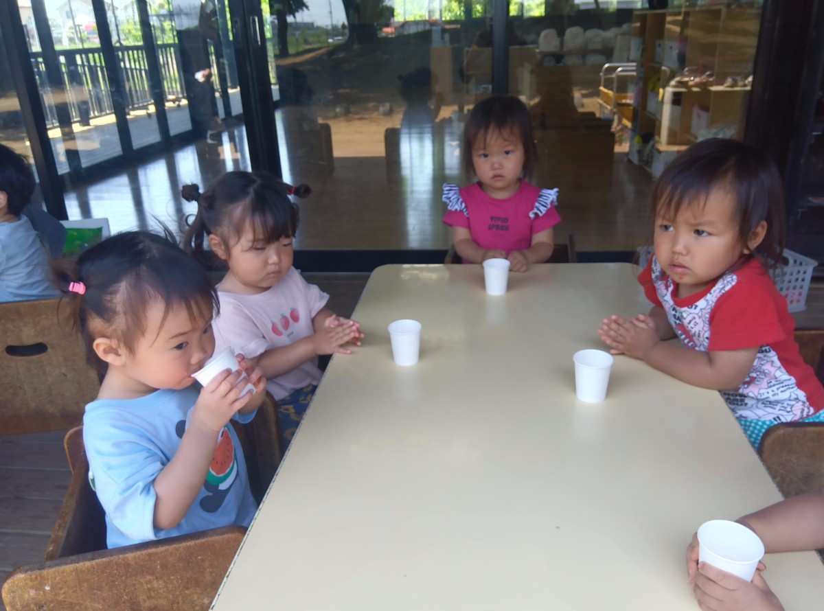 机には、紙コップを持っている子、紙コップに入ったイチゴジュースを飲んでいる子、手を合わせている子などがいる