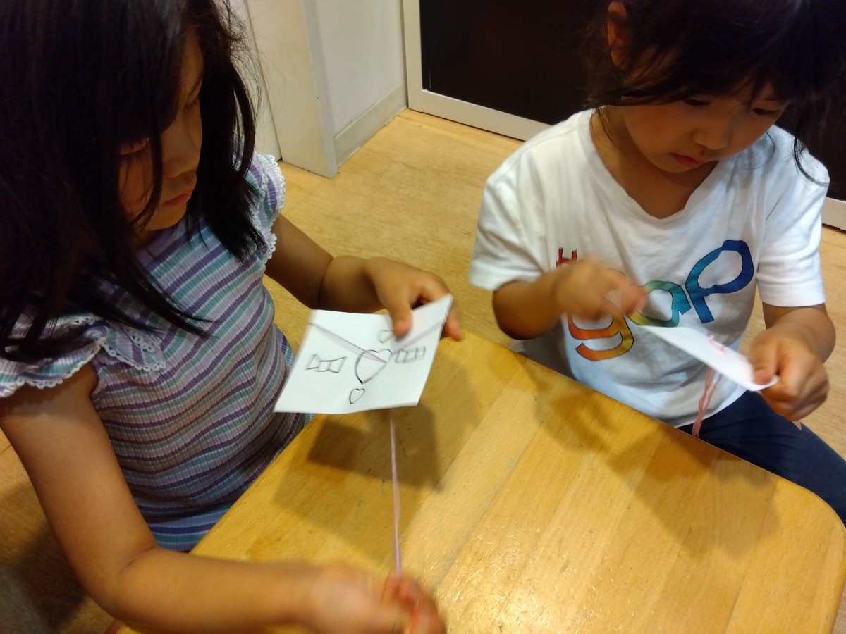 二人の子どもが柄が描かれた画用紙を針で縫っている