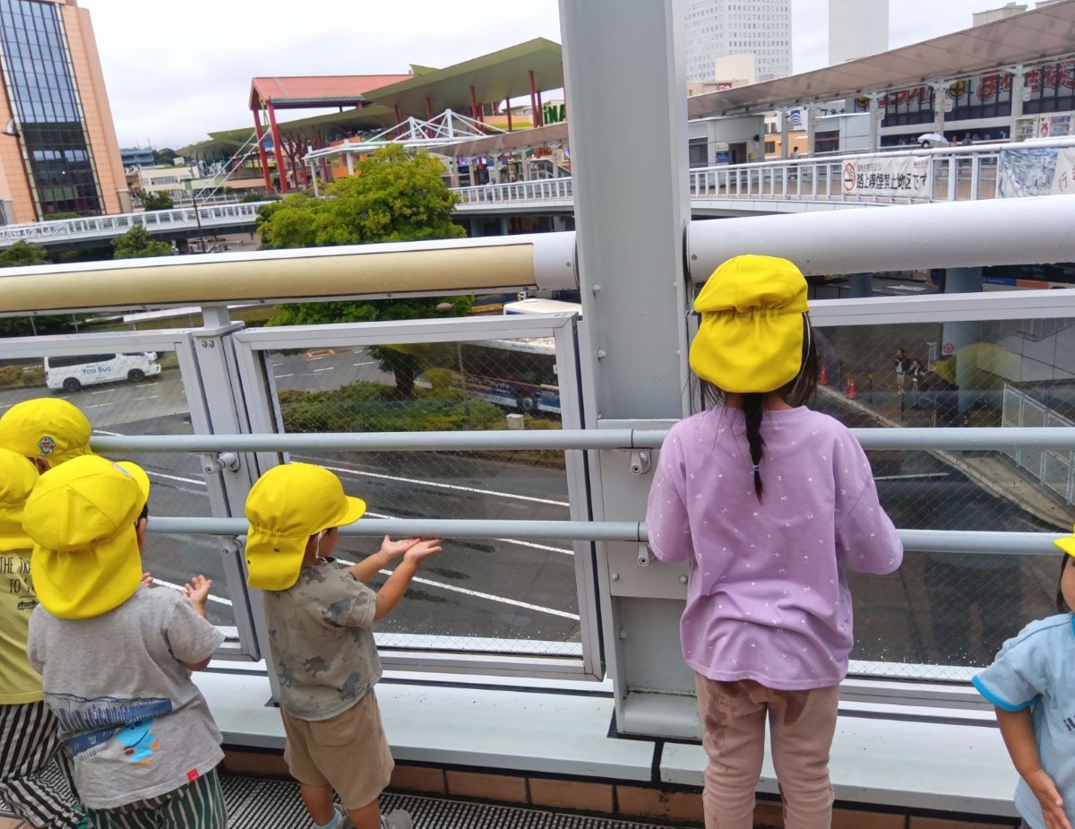 雨上がりに、子どもたちは通路の手すりの水滴を両手で触っている