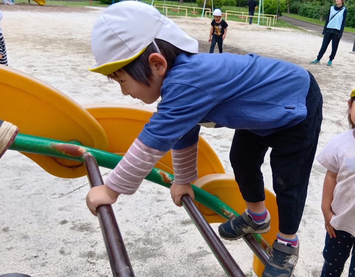 子どもたちが順番に雲梯の上を高這いで登っている