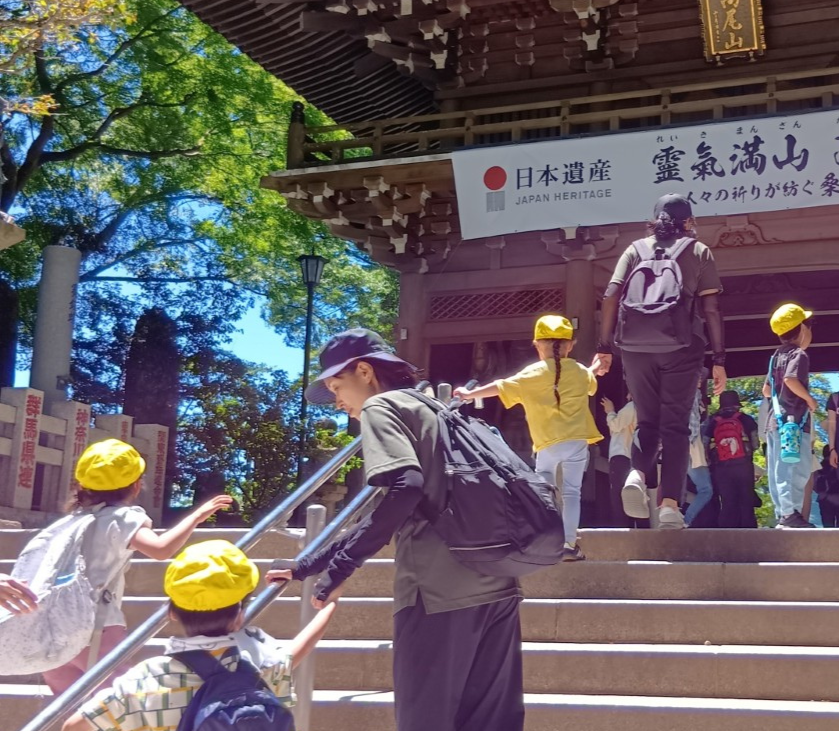 大人と子どもたちは薬王院の入口の階段を上っている