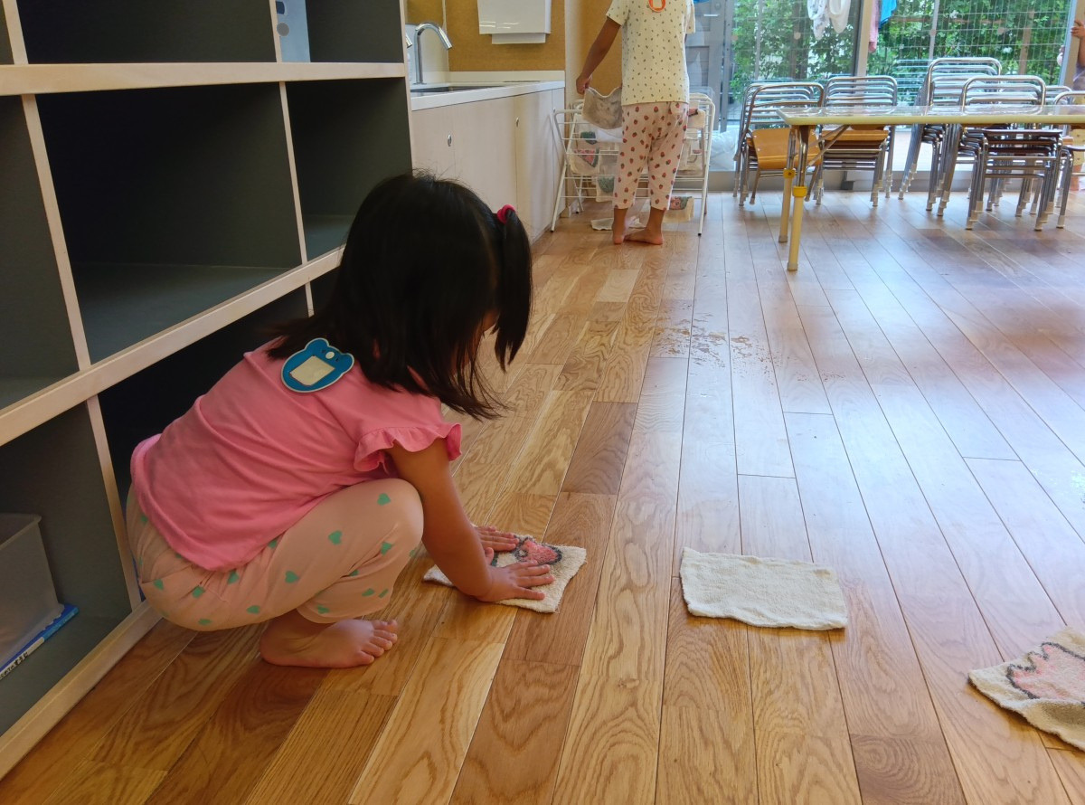 滑り台の上で滑り降りようとしているこども