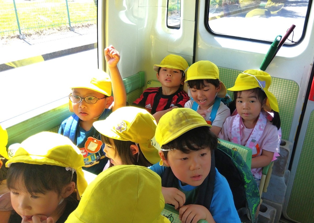 子どもたちは一つのシートに３人ずつ並んで座りバスに乗っている