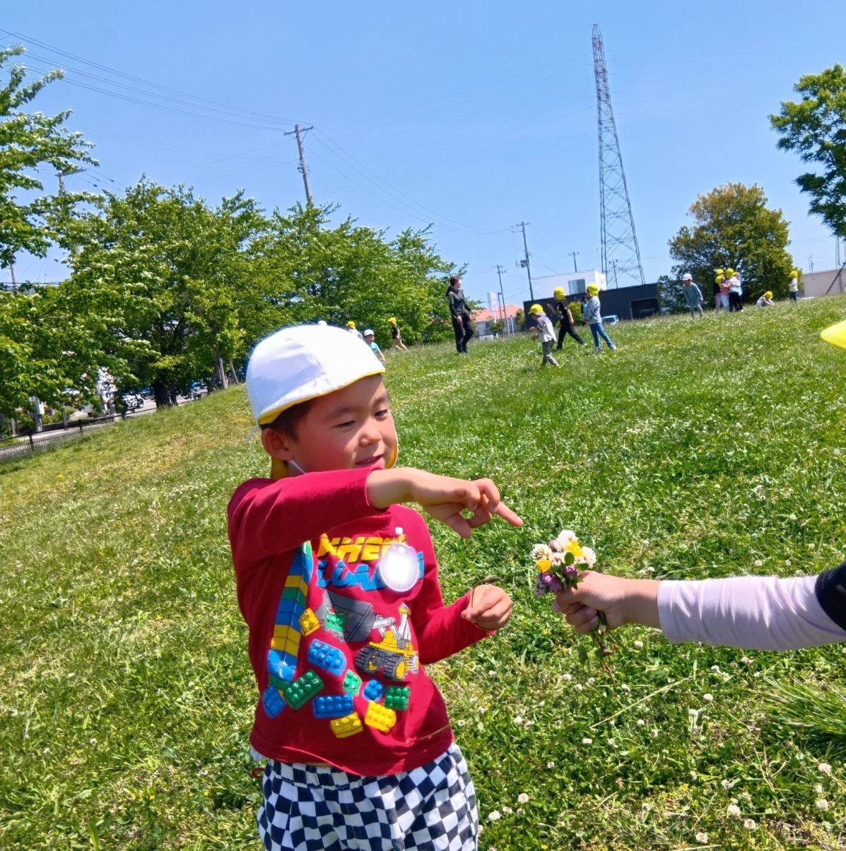 一人の子どもが大人が差し出した花束を笑顔で指さしている