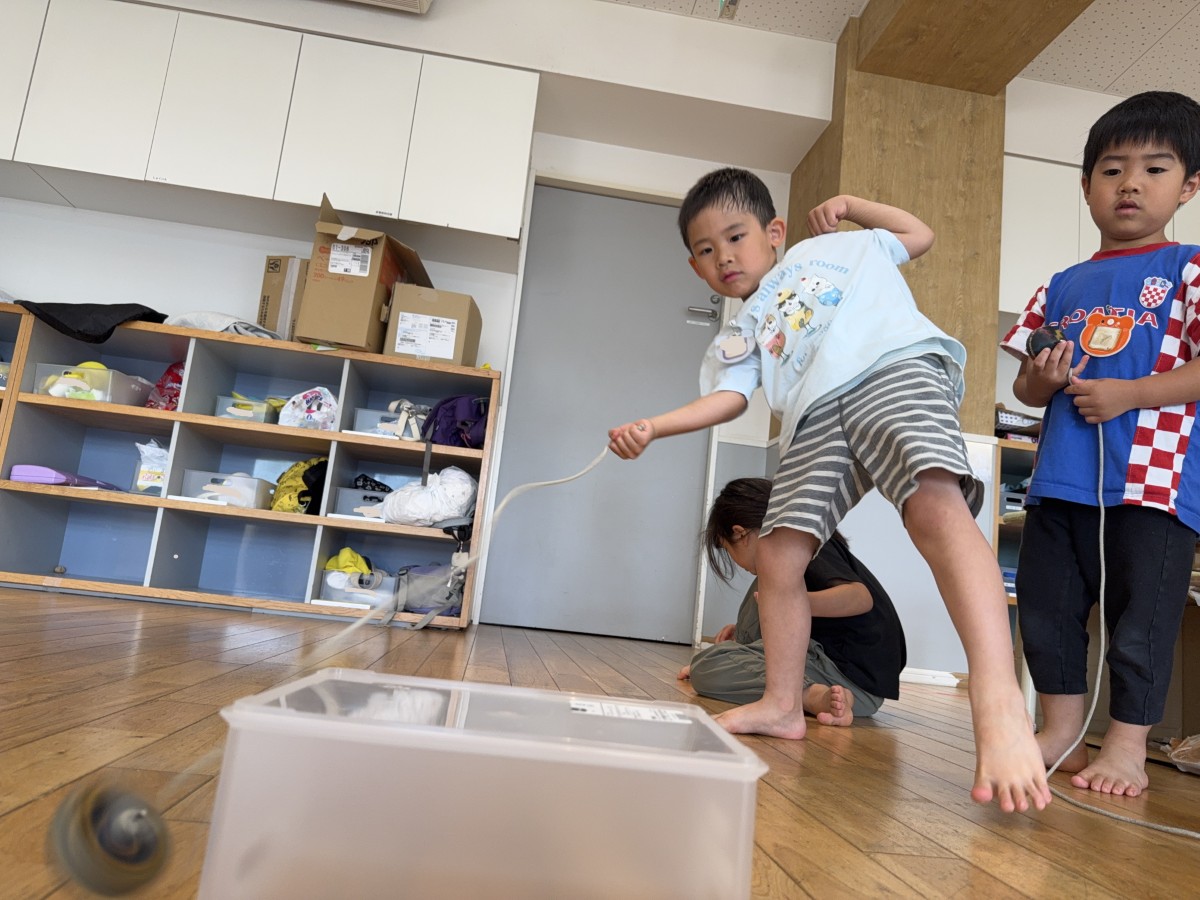一人の子どもが体を傾けてコマ回し台を狙いコマを投げている