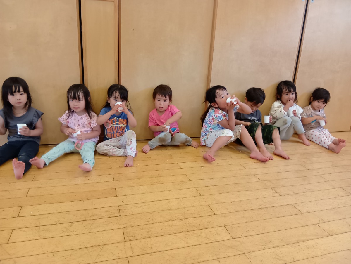 一列に並んで座っているこどもたちは、紙コップに入ったこふきいもを手で食べている