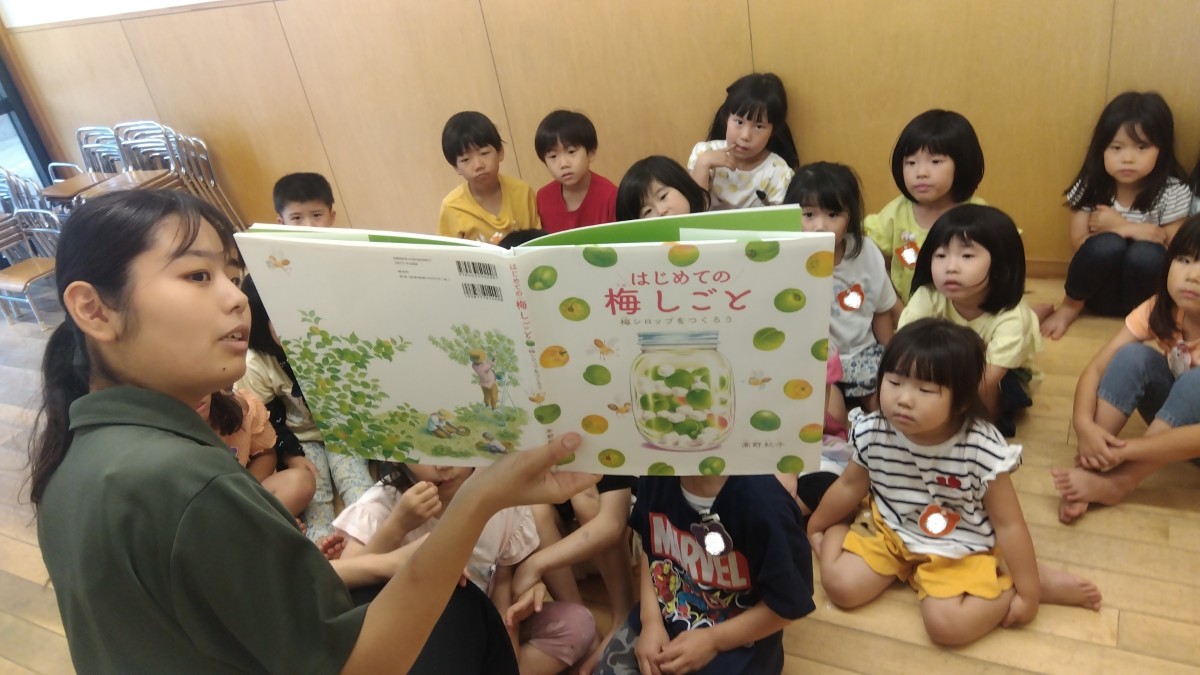 一人の大人が「はじめての梅しごと」という絵本を子どもたちに読み聞かせをしている