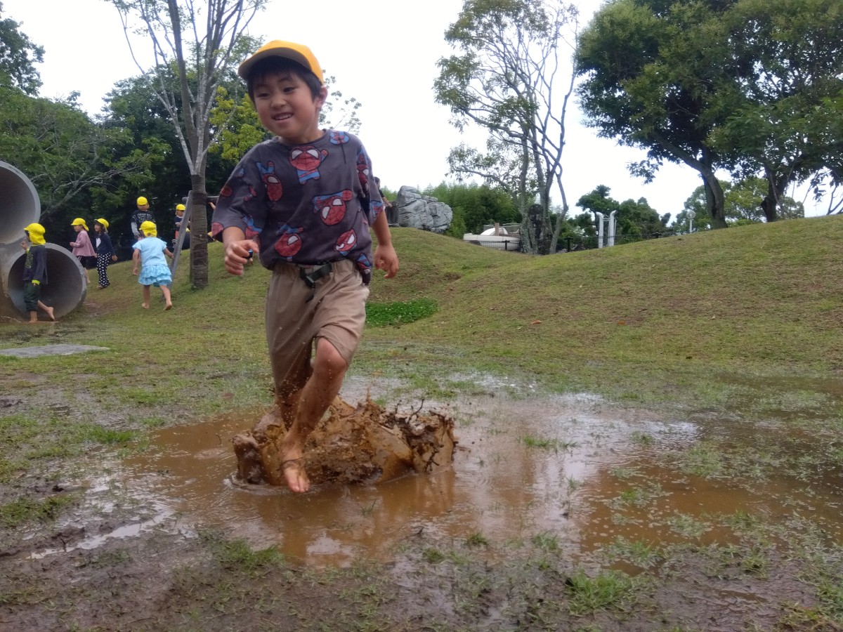 一人の子どもが泥水の中をしぶきを立てて走ている