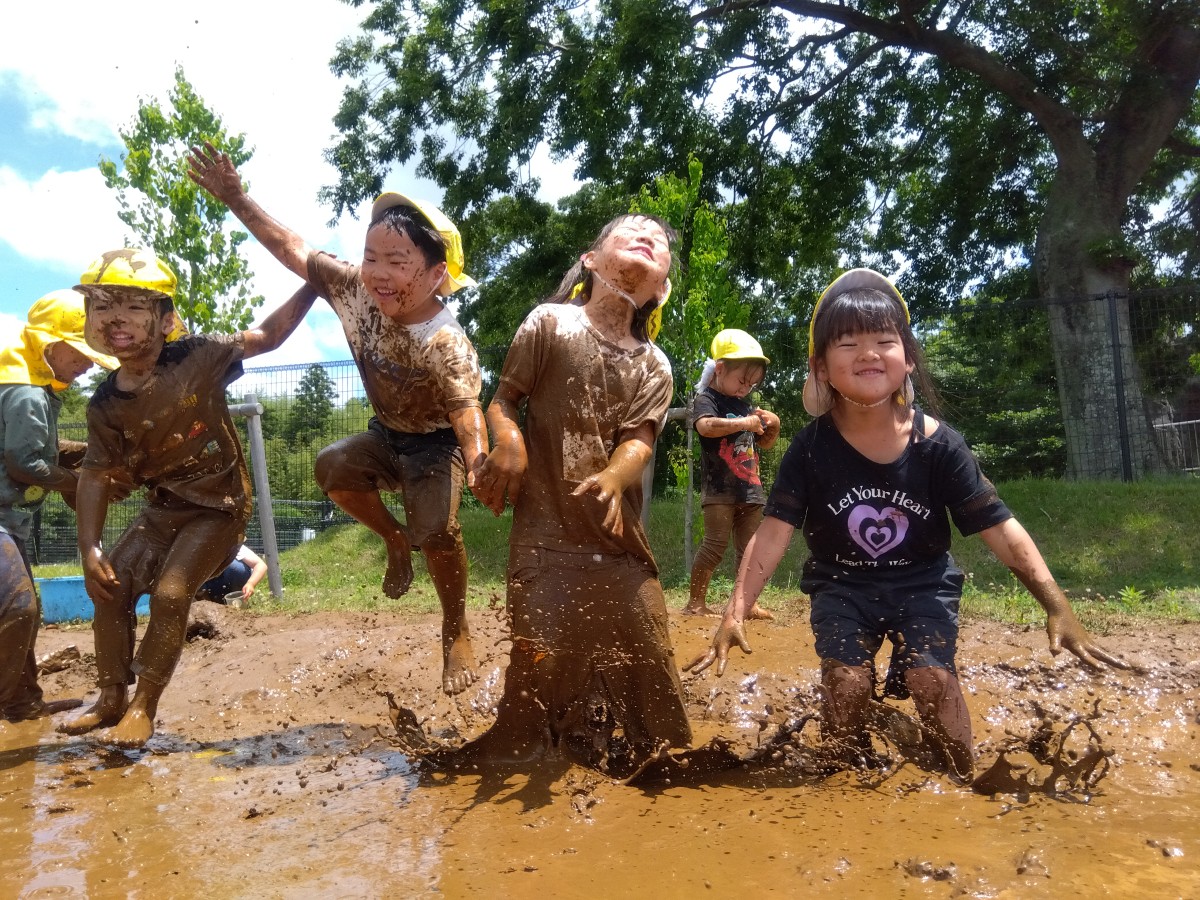 全身泥だらけの子どもたちが、泥水の中でジャンプしている