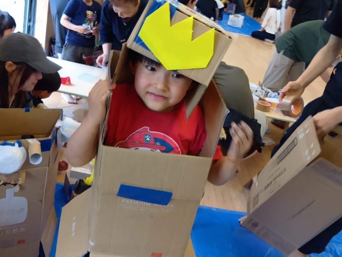 一人の子どもが段ボールで作った帽子と洋服を身に付けている