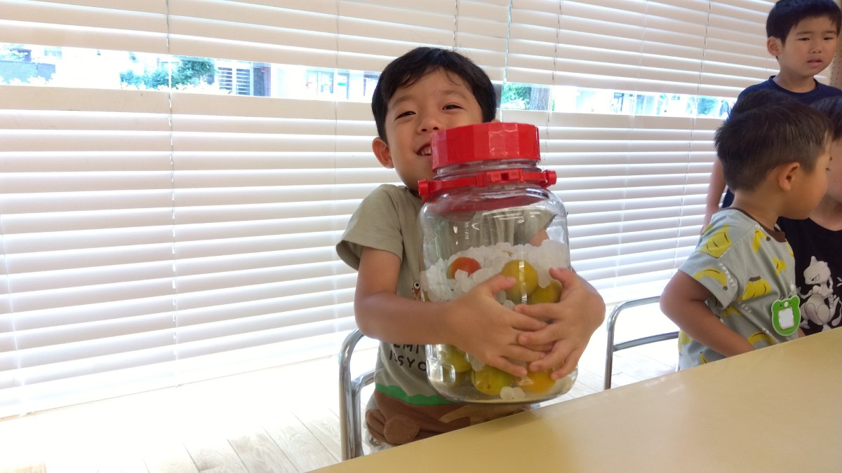 一人の子どもが角砂糖と梅が交互に入った瓶を抱えて笑っている