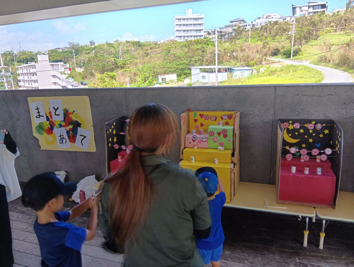 的当てコーナーでは子どもたちが的に向かって割りばし銃を向けている