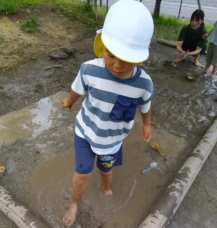 一人の子どもが泥の中を裸足で歩いている