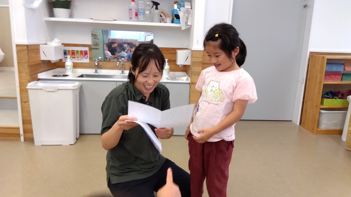 スタッフと子どもが一緒に手紙を読んで笑顔を見せている