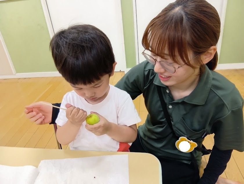 一人の子どもが竹串を握り、真剣な表情で梅干しのヘタの部分に竹串をあてている