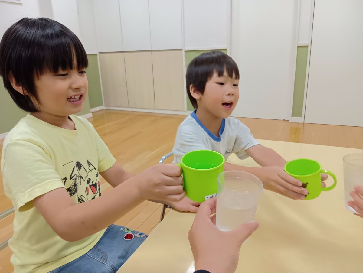 子どもたちと大人は梅ジュースが入ったコップで乾杯をしている