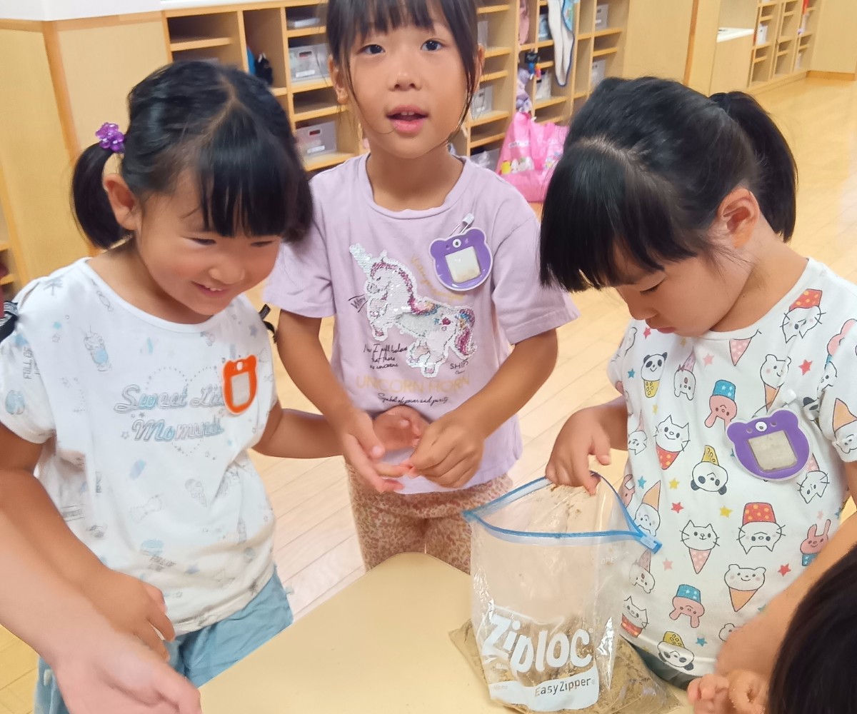 机の上にはぬかが入ったジッパー付きポリ袋が置いてあり、その中を覗き込む子、ぬかを触った指の感触を楽しむ子、大人に話しかける子などがいる