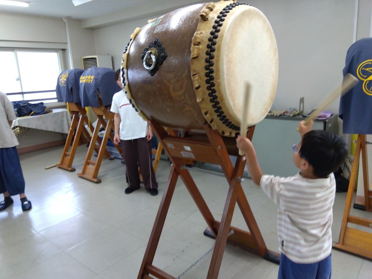 一人の子どもは、横向きに置いてある和太鼓の面をバチを使って叩いている