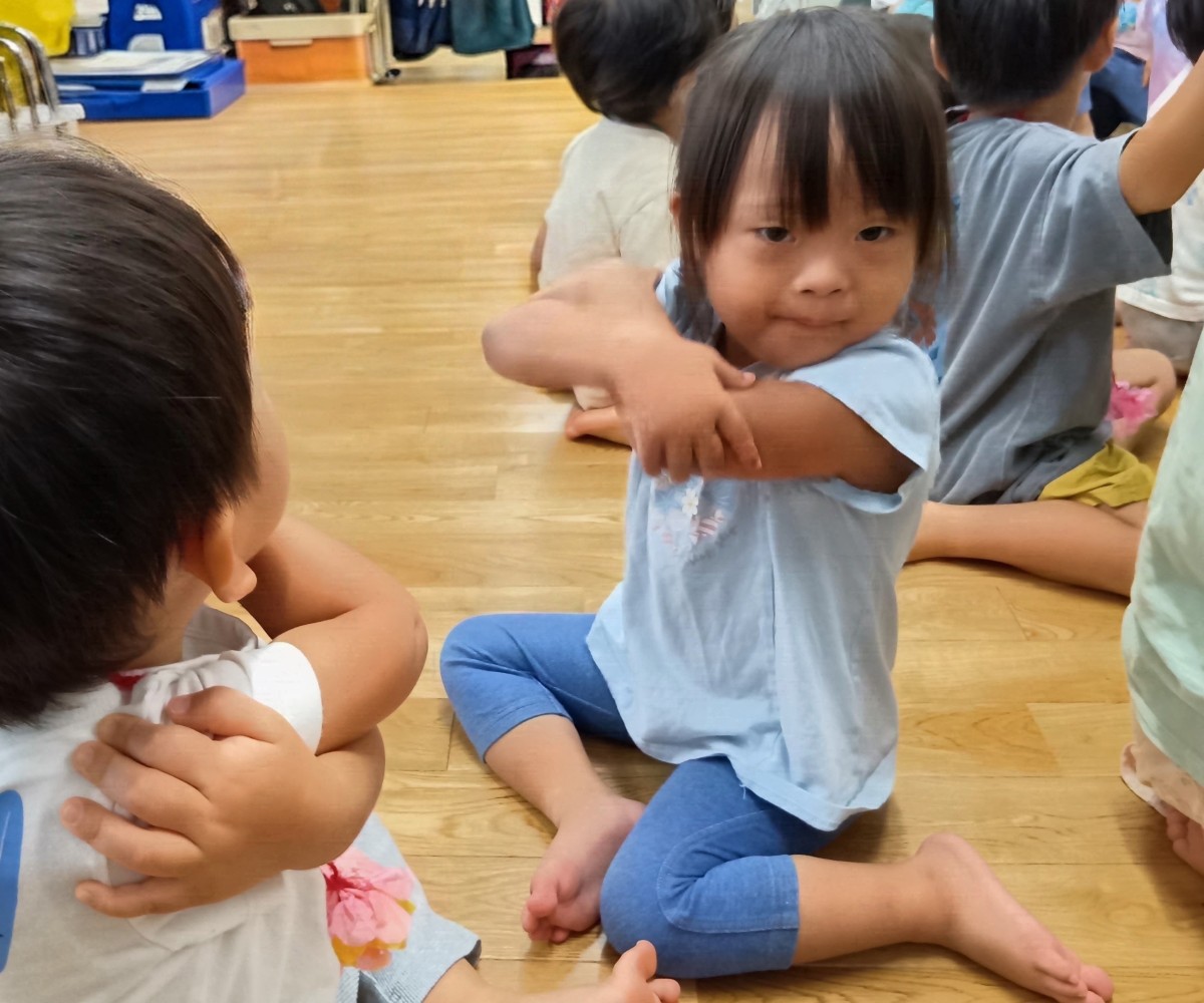 子どもたちは、両腕を体の前で交差させて自分の肩や肘をつかんでいる