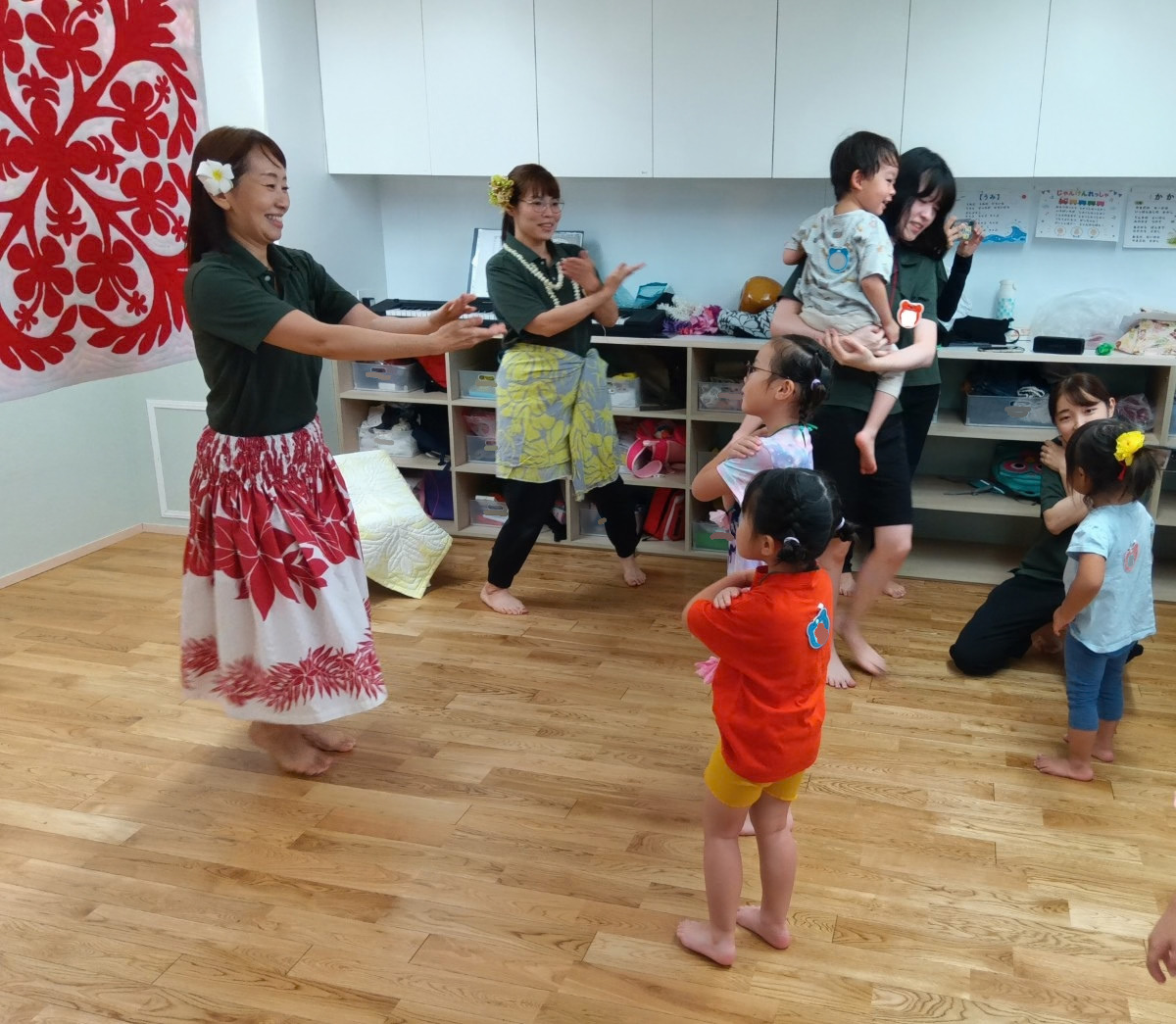 パウスカートを履いた大人が前に立ち、子どもたちは前の大人を見ながら真似して手を動かそうとしている