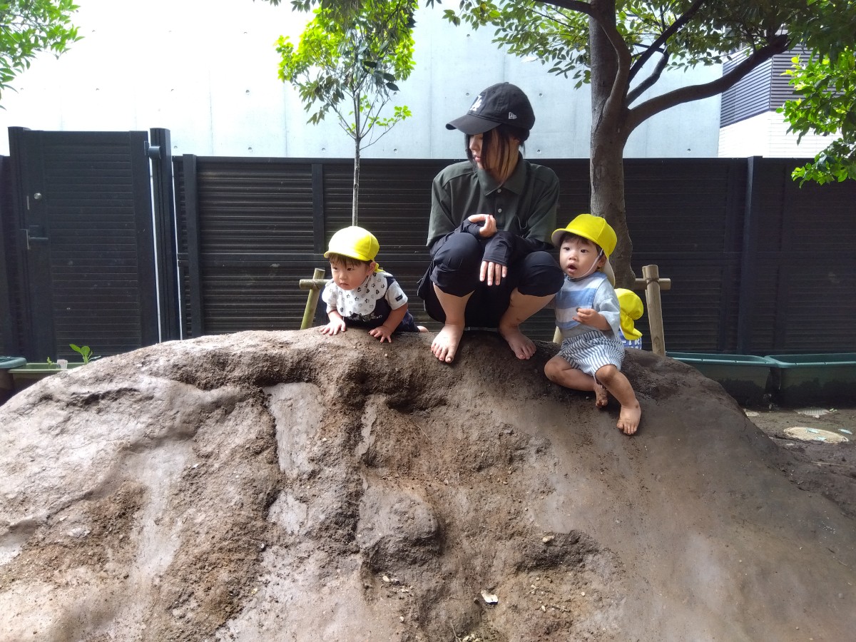 大人と子どもたちが築山の頂上に座っている
