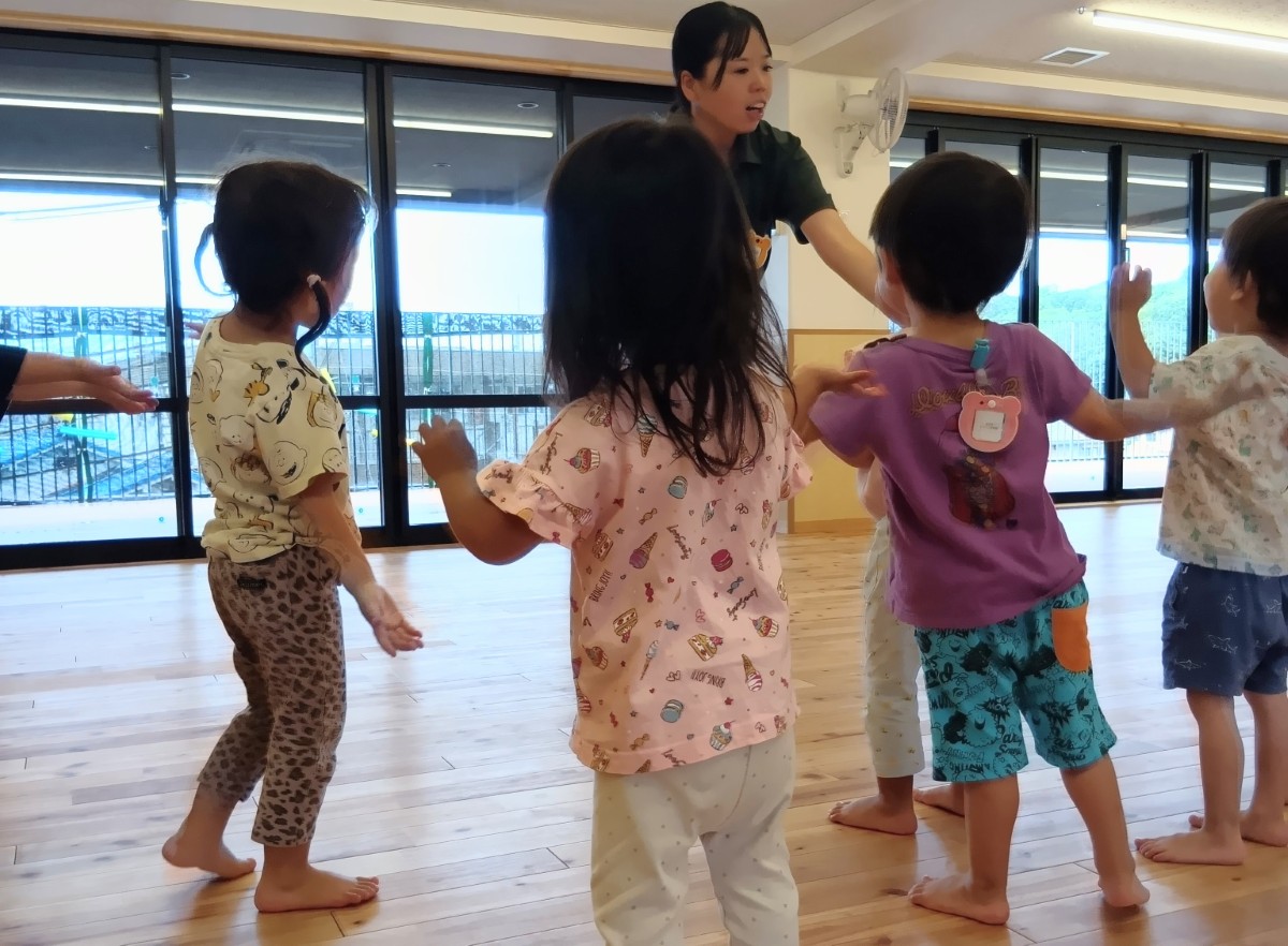子どもたちは、前に立っている大人の動きを真似して両腕を動かしている
