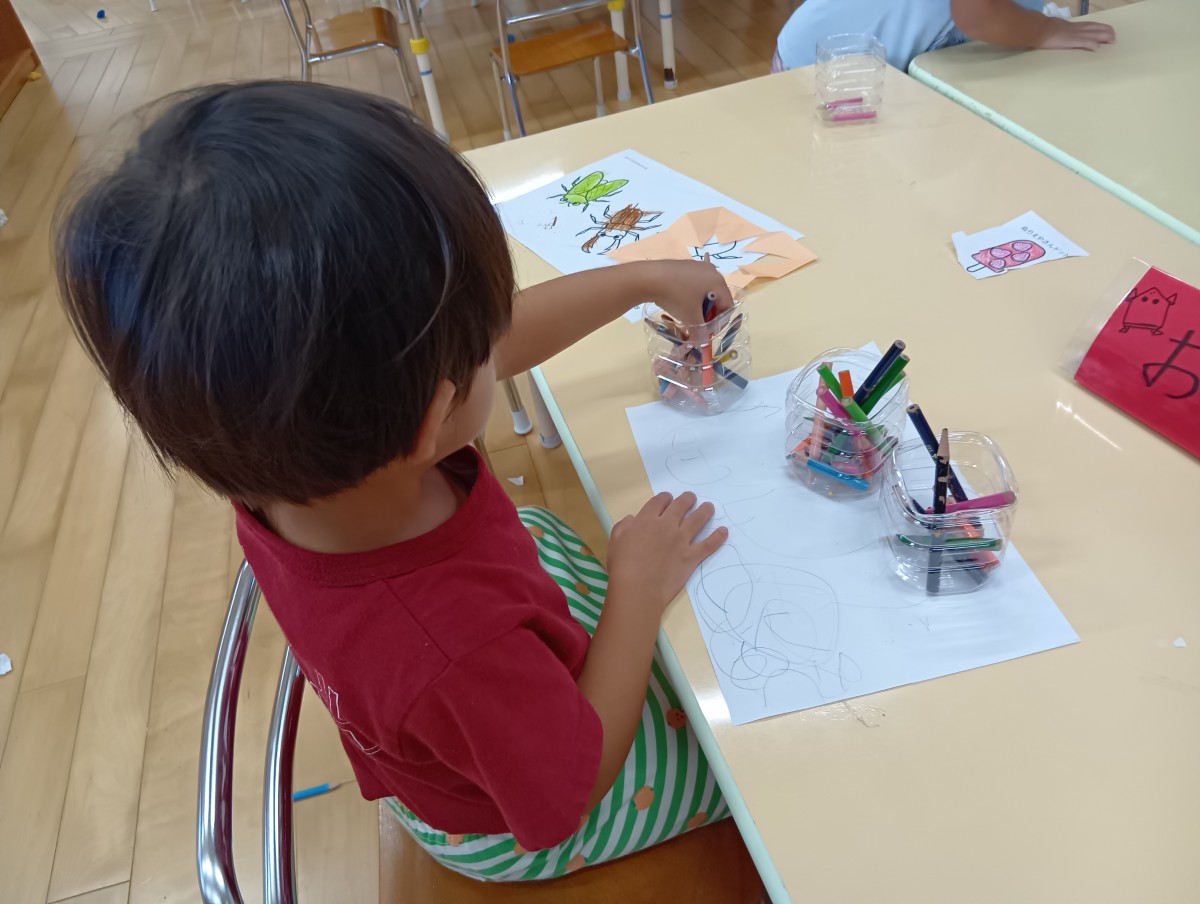 先程の一人の子どもが、色鉛筆を自ら選び手に取ろうとしている