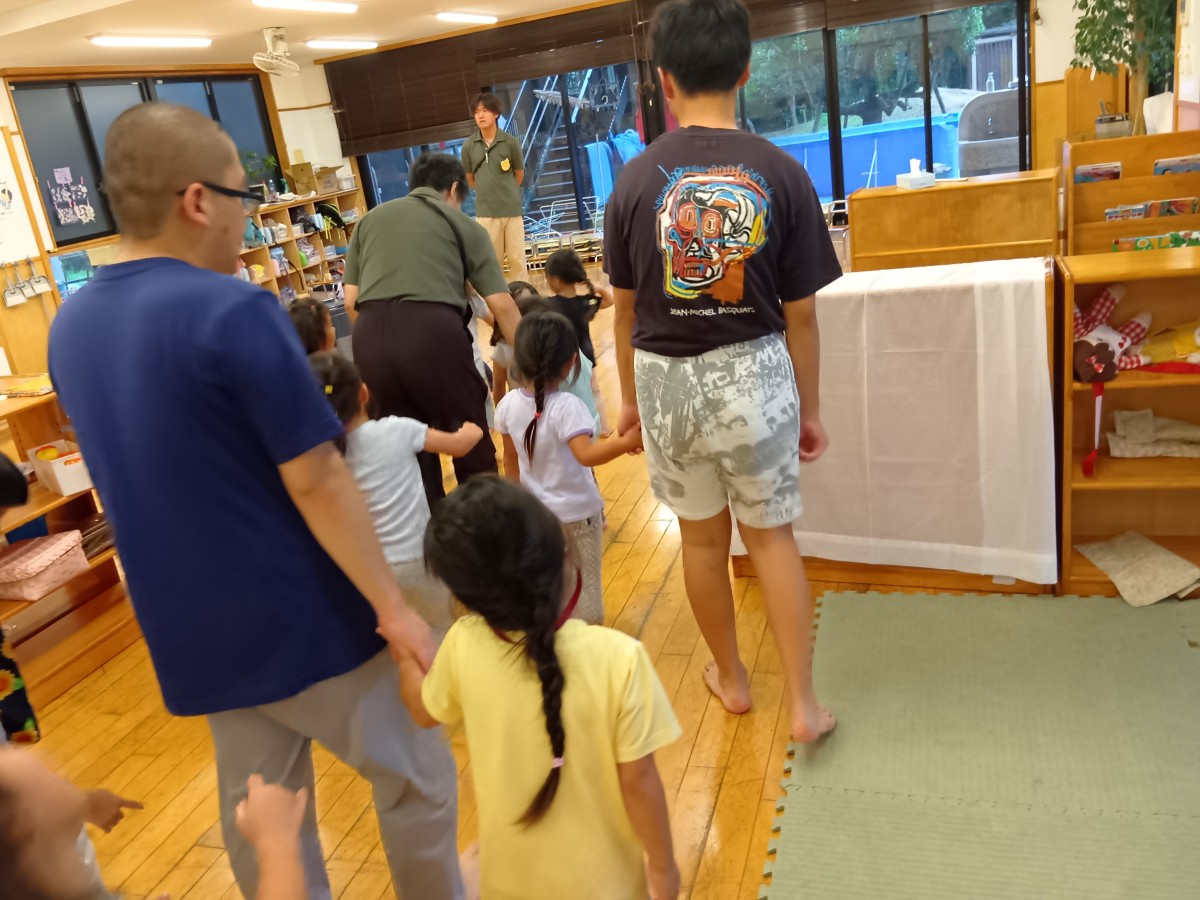 大人と子どもが手をつなぎ、室内に集まってきている