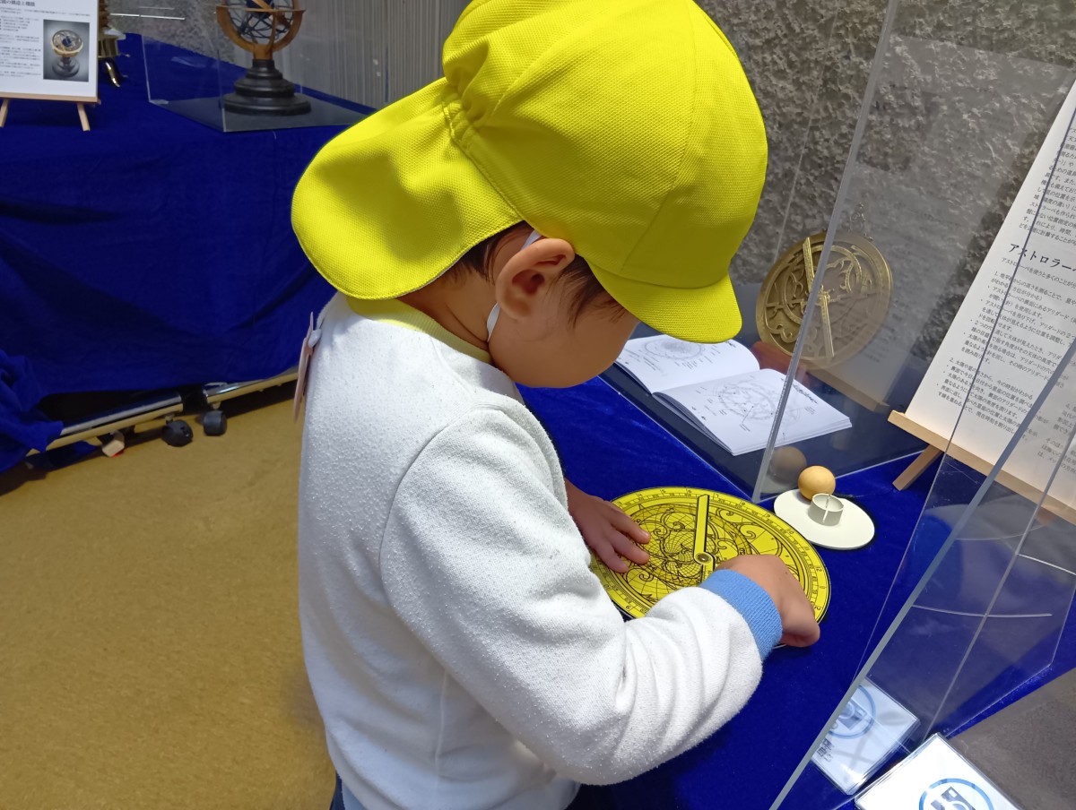 一人の子どもがアストロラーベの模型を触っている