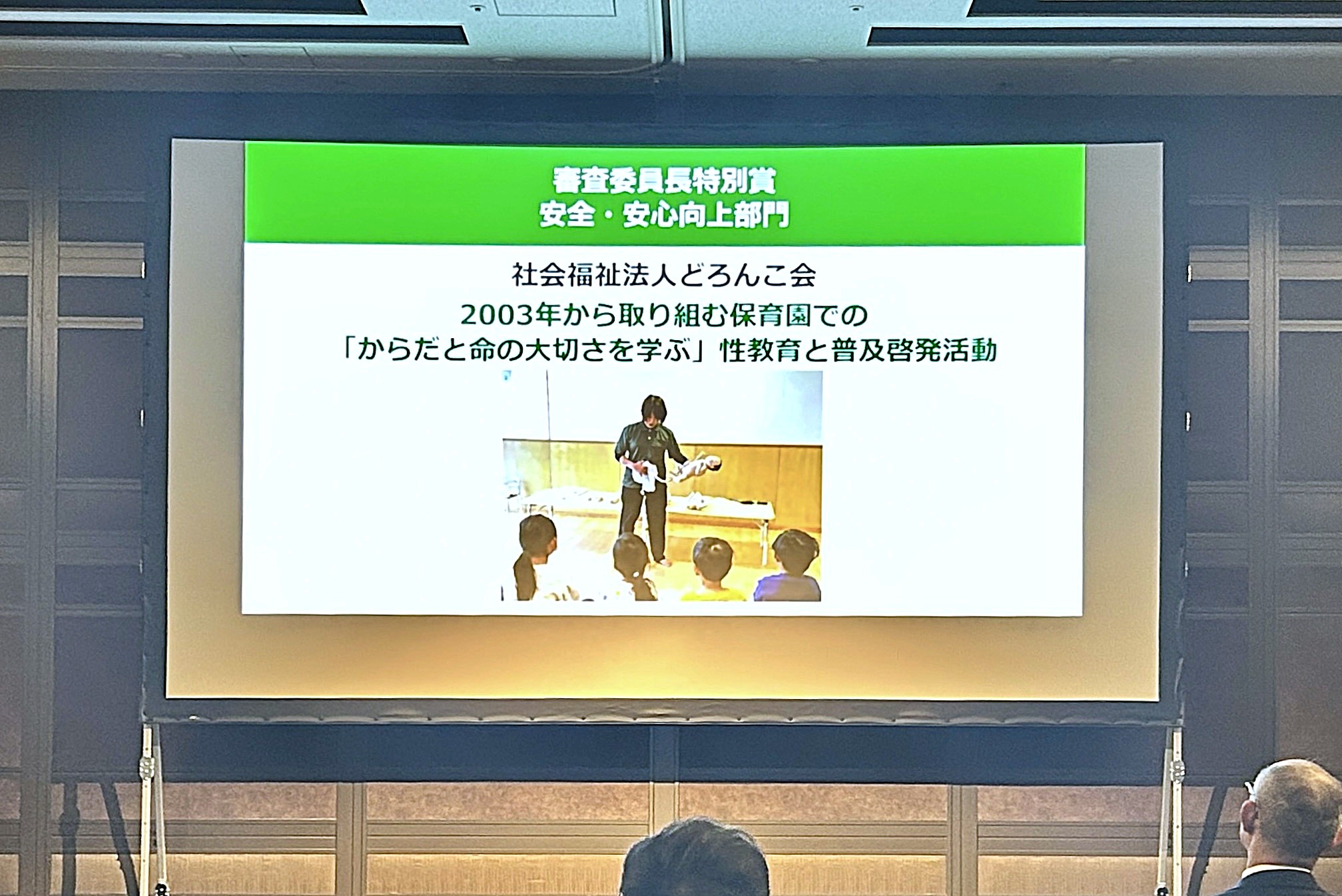 受賞内容とイメージ写真がスクリーンに写されている様子